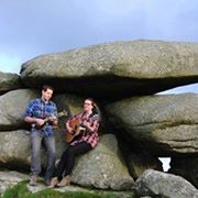 man and woman playing instruments while sitting on granite rock
